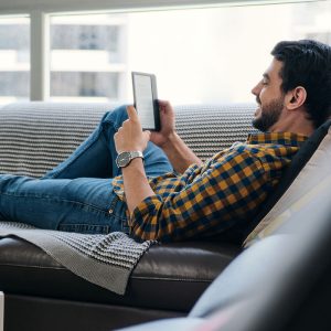 Uomo che legge un ebook sul divano in salotto